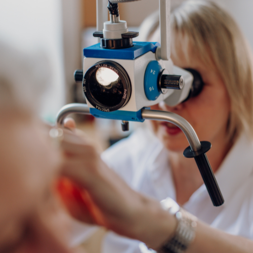 Ein Bild einer HNO-Ärztin, die ein spezielles Mikroskop benutzt, um das Ohr eines Patienten zu untersuchen. Die Ärztin trägt eine Brille und konzentriert sich auf das Mikroskop, während der Patient in einer Behandlungseinheit sitzt. Dieses Bild unterstreicht die Verwendung modernster Technologien zur genauen Diagnose und Behandlung in der Praxis.